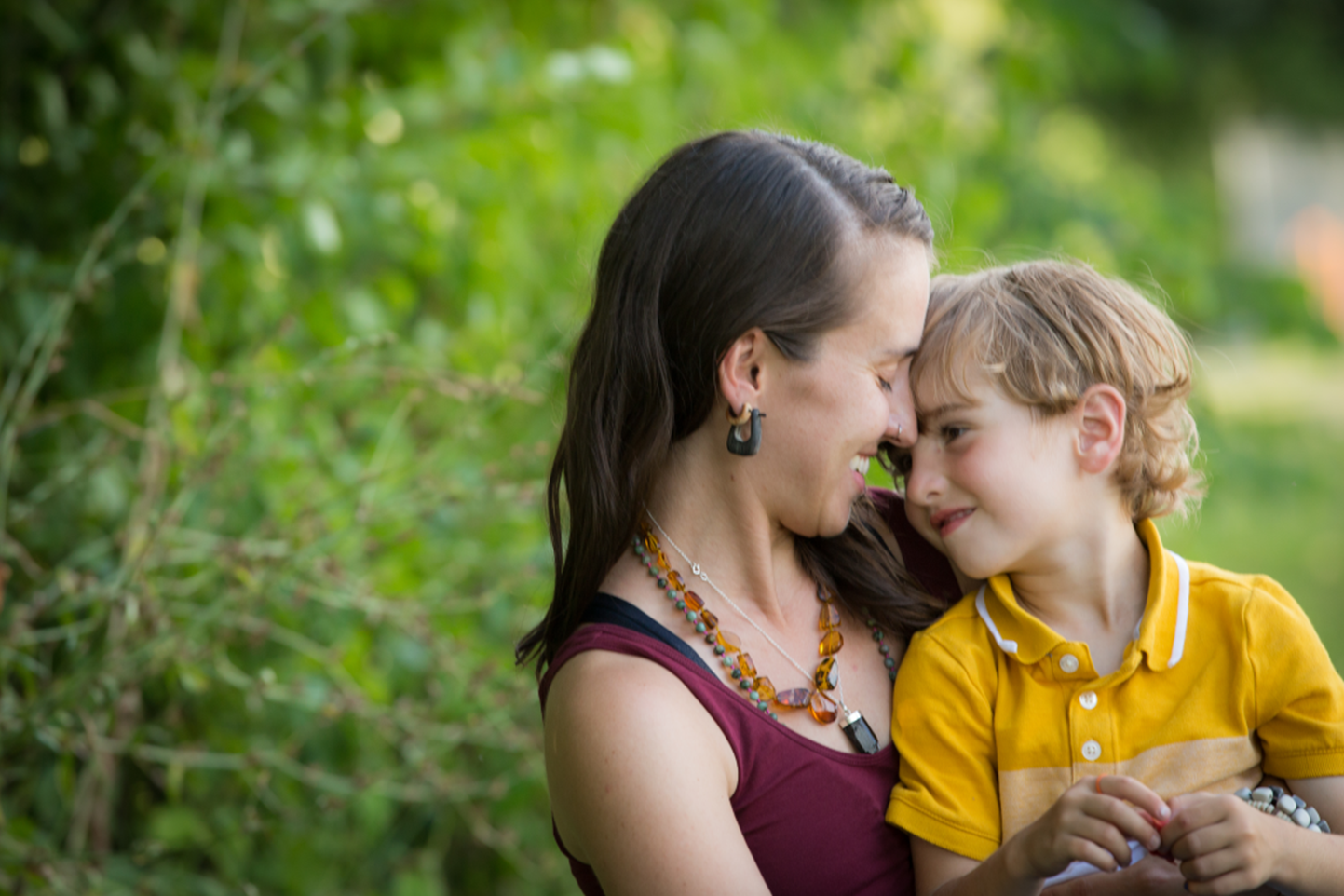 Smiling mother hugging son sitting in field son